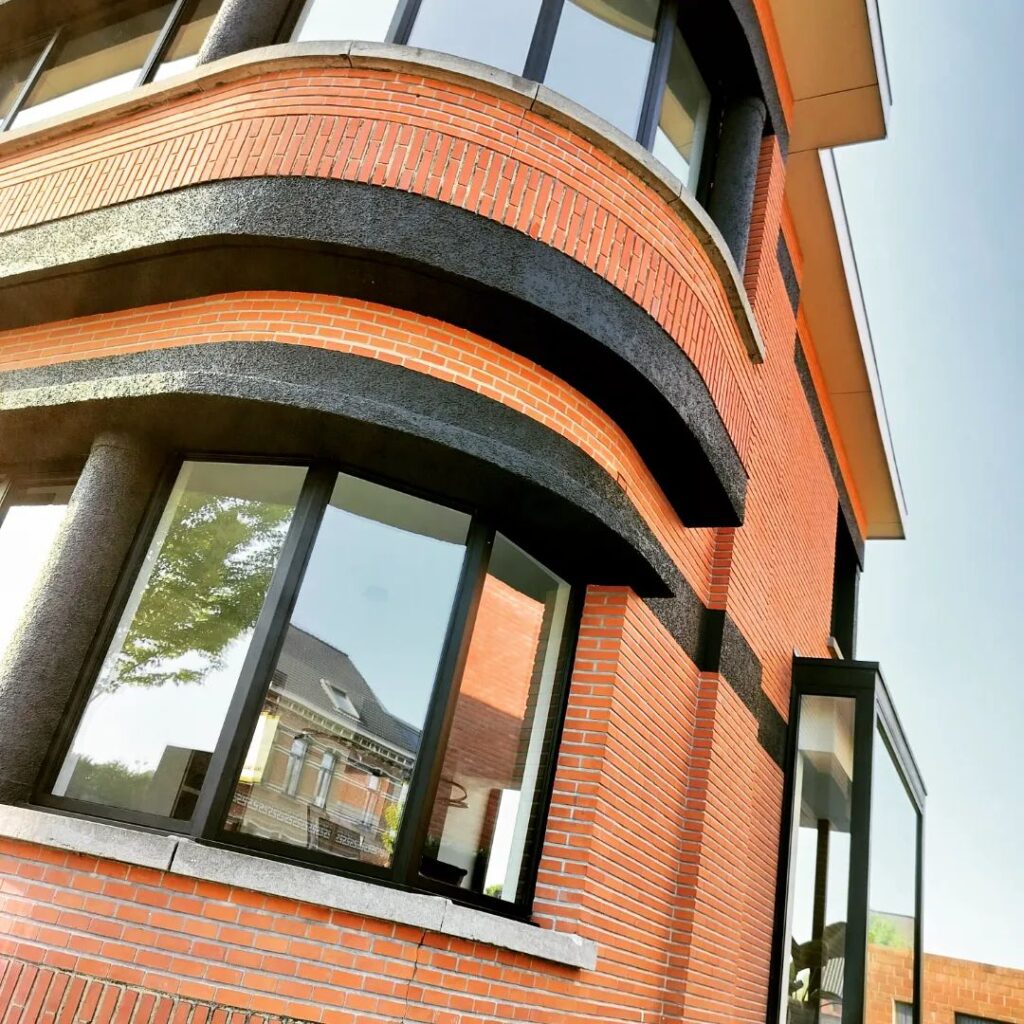 Woning in rode baksteen met gebogen gevel en donkere kroonlijst
