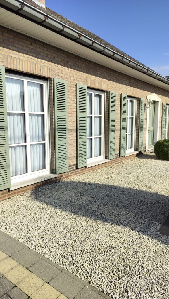 Bungalow met groengrijs geschilderde luiken na het schilderwerk